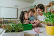 Teacher with children planting a plant in a pot in kindergarten