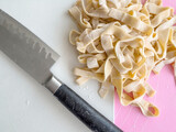 Fototapeta Tulipany - hand cut raw pasta and knife on cutting board
