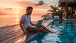 © Nemanja - Young man sitting poolside by the swimming pool working on laptop notebook computer during sunset. Tropical island summer vacation or holiday remote online work on the internet, freelancer