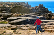 Brave senior woman riding her electric mountain bike on the rocky cliffs of Peniche at the western atlantic coast of Portugal