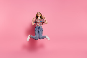 Sticker - Full length photo of lovely teen jump headphones point look up empty space dressed stylish print clothes isolated on pink color background