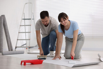 Sticker - Couple applying glue onto wallpaper sheet in room