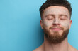 © New Africa - Handsome man with facial mask on his face against light blue background, space for text
