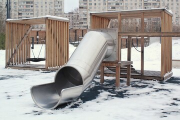 Wall Mural - Wooden playground made of natural eco-friendly material in public city park with snow at winter time. Modern safety children outdoor equipment. Winter activities. Children rest and games on open air