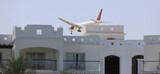 Fototapeta Desenie - passenger plane lands over a building