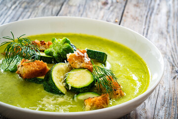 Poster - Cream zucchini soup with croutons, Parmesan cheese and fresh dill on wooden table
