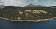 Scotland, Brodick ocean bay aerial view: alone sailboat at Firth-of-Clyde Gulf water against Scottish nature landscape. Beautiful mountains at horizon with wide woods. Panorama scenery shot
