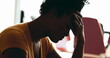 Young African American woman struggles with depression at home in quiet despair feeling overwhelmed by stress and sorrow putting hands on side temples feeling headache