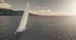 Sun reflection over yacht cruising at crystal sea bay aerial. Mesmerezing seascape with sail boat at summer bright sunlight day. Serene waterfront with alone sailboat at windy wheather at drone shot