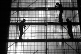 Fototapeta Londyn - Amidst the stark contrast of black and white tiles, workers labor on, their silhouettes etched against the backdrop of industrial progress.