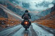 A lone motorcyclist navigates a winding mountainous road amidst the enveloping fog and stark landscape