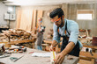 © chokniti - Diligently skilled man work with wood in carpenter's shop, using tools and equipment to transform timber planks into bespoke wooden pieces, craftsmen workshop with natural material, furniture industry