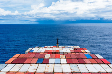 Wall Mural - View on the containers loaded on deck of the large cargo ship. She is sailing through calm, blue ocean. 