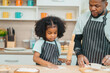 © chokniti - In a home kitchen, black father and his daughter bond over cooking a meal food, their laughter and love filling the air, embodying the joy of African American family life, Father's Day concept