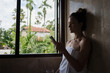 © EASY 2 SHOOT/Stocksy - Woman in Towel Scrolling on Her Phone Near Opened Window