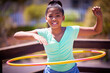 © peopleimages.com - Happy girl, portrait and playing with plastic hoop at park for fun game, activity or outdoor exercise. Young teenager or female person with smile for hula practice, twist or motion at playground