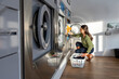 © Santi Nuñez/Stocksy - Woman doing laundry in the laundromat shop