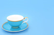 Blue and gold bone china tea cup. Elegant luxury drinking set on pastel blue background with copy space. Minimal zen composition.
