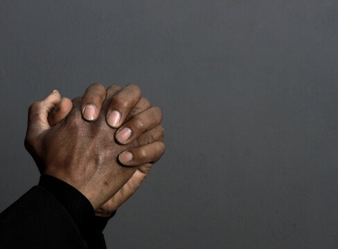 man praying to god with hands together Caribbean man praying on black background with people stock photos stock photo stock image