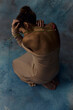 © Iuliia Versta/Stocksy - a woman with bare shoulders sits on a blue background