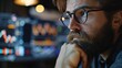 Bearded man trader wearing eyeglasses sitting at desk at office monitoring stock market looking at monitors analyzing candle bar price flow touching chin concerned trading concept close-up