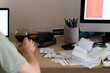 © Ivan Haidutski/Stocksy - man works online at messy workplace with receipts, invoices