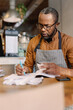 © Oleksii Syrotkin/Stocksy - Barista comparing information in ledger