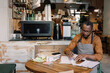 © Oleksii Syrotkin/Stocksy - Barista handling accounting