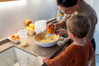 © Santi Nuñez/Stocksy - Happy family cooking together