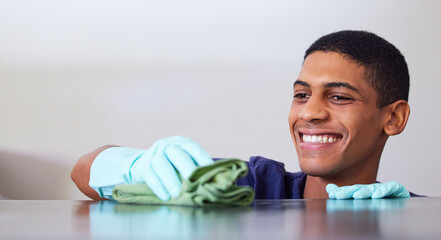 Young man, smile and cleaning a kitchen counter, housekeeping and disinfecting surface with cloth. Gloves, safety and wipe furniture with rag for hygiene, house work and domestic chores at home