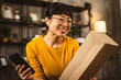 © Miljan Živković - japanese woman checking box of received package or product at home
