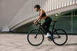 Active female cyclist in sportswear helmet cycle outdoors on city building background