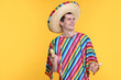 © New Africa - Young man in Mexican sombrero hat and poncho with maracas on yellow background. Space for text