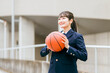 校舎の前でバスケットボールを持つ女子中学生・女子高生（部活・スポーツ・運動部・バスケ部）
