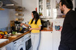 © Jimena Roquero/Stocksy - Couple in the kitchen cooking veggies on pan on stove while talking