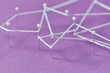© Yaroslav Danylchenko/Stocksy - White thread tying chaotically stationery pins on violet background