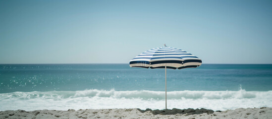 Retro vintage navy white stripe beach umbrella French parasol on sand sunny summer beach sea waves cloud sky earthy natural color vacation relaxation seaside coast resort ocean vibes summer holiday 