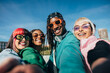 © VICTOR TORRES/Stocksy - Diverse group of friends sharing a cheerful moment while taking selfie