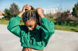 © VICTOR TORRES/Stocksy - Young black woman putting up her braided hair outdoors