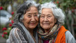 Two elderly women with gray hair hugging and smiling.