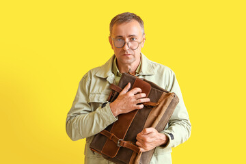 Wall Mural - Stressed mature man with briefcase on yellow background. Deadline concept