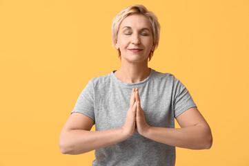 Sticker - Portrait of meditating mature woman on yellow background