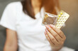 Contraceptive means: Woman hand holding contraceptive pills and condom sitting on sofa background. Protection, safe sex. Contraception, concept birth control. Copy space