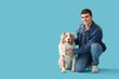Young man with Australian Shepherd dog on blue background