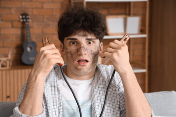 Wall Mural - Electrocuted young man with burn face and jumper cables at home, closeup