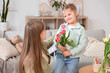 © Pixel-Shot - Little daughter greeting her mom with bouquet of tulips at home. Mothers Day celebration