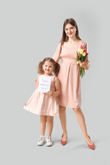 Wall Mural - Little girl and her mom with bouquet of tulips and greeting card on grey background. Mothers Day celebration