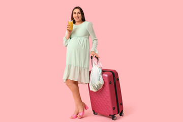 Poster - Young pregnant woman with suitcase and cocktail on pink background. Travel concept