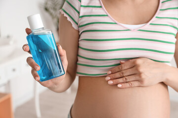 Sticker - Young pregnant woman with mouth rinse in white bathroom, closeup