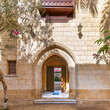 Sunlight filters through an ornate stone archway leading into a serene courtyard